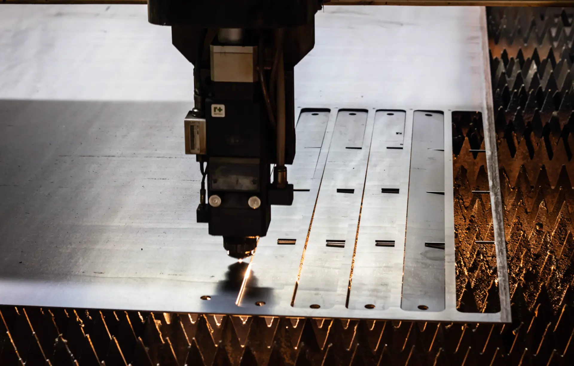 CNC fibre laser head cutting profiles from a steel plate