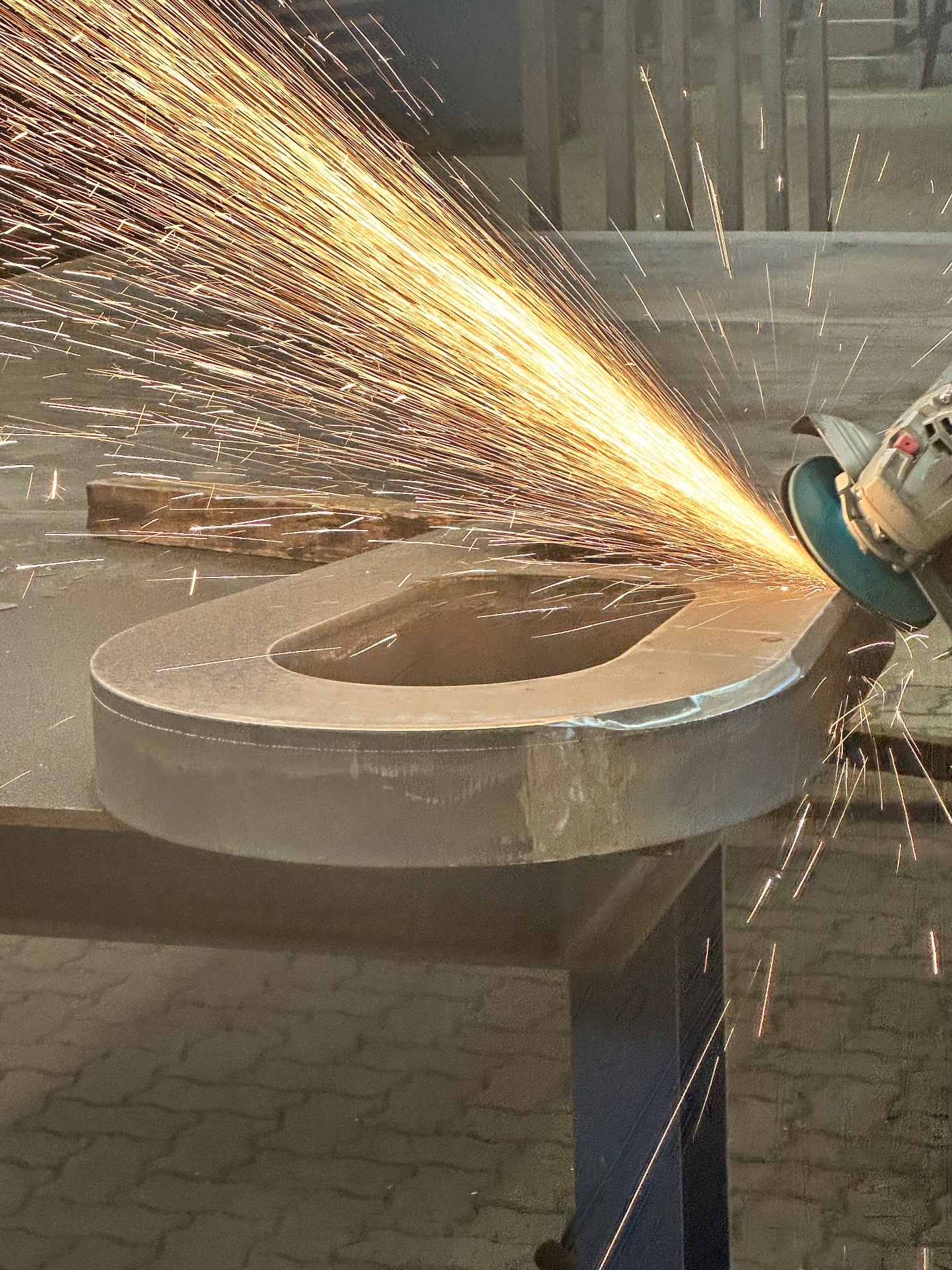 Operator grinding the edge of a heavy S690 chain link, sparks flying